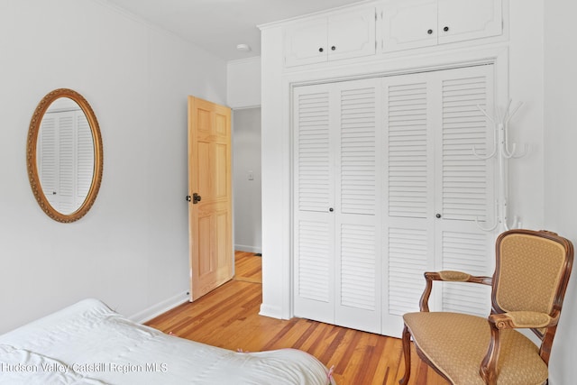 bedroom with crown molding, a closet, and light hardwood / wood-style floors