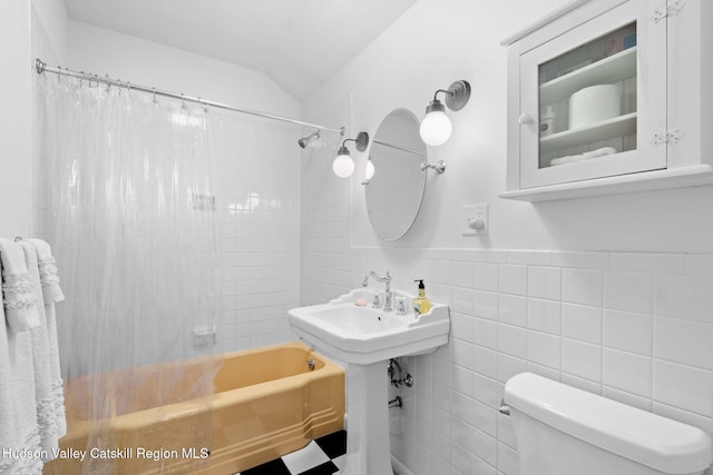 bathroom with shower / bath combo, toilet, tile walls, and vaulted ceiling