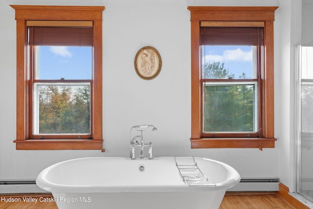 bathroom with a bathing tub, hardwood / wood-style floors, and a baseboard heating unit