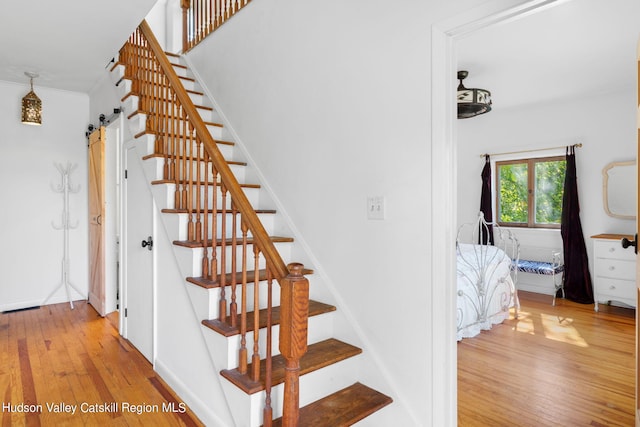 stairway with a barn door and hardwood / wood-style flooring