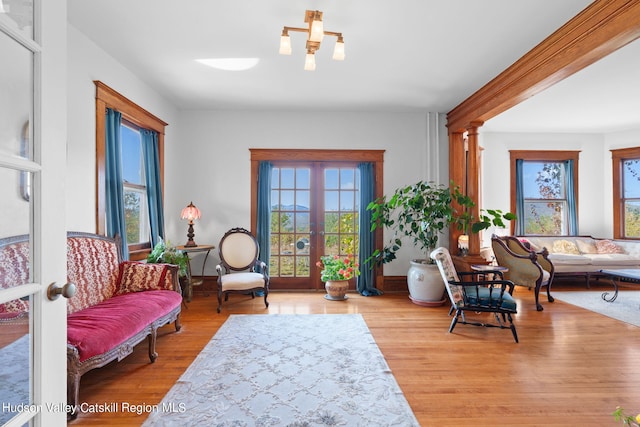 sitting room with french doors, light hardwood / wood-style floors, a wealth of natural light, and decorative columns