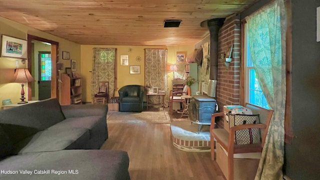 living area with wood ceiling, a wood stove, and light hardwood / wood-style floors