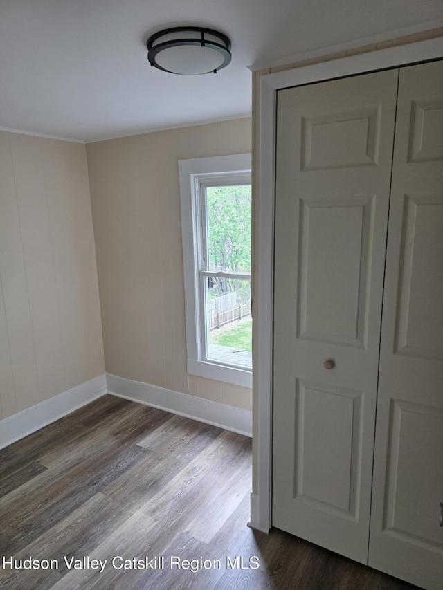 spare room with baseboards and wood finished floors