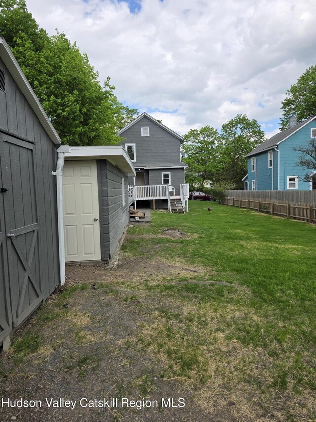 view of yard featuring a storage shed, an outdoor structure, and a deck