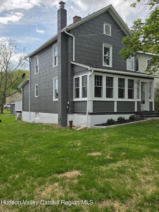 back of property with a chimney and a yard