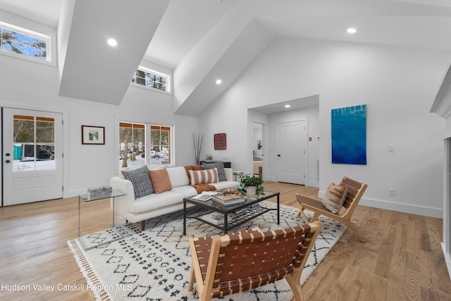 living area featuring high vaulted ceiling, light wood finished floors, recessed lighting, and baseboards