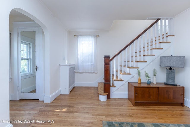 entryway with light wood-type flooring and ornamental molding