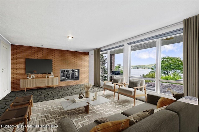 living room featuring brick wall, a water view, and a fireplace