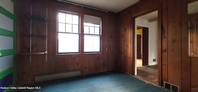 spare room with wood walls and a baseboard radiator