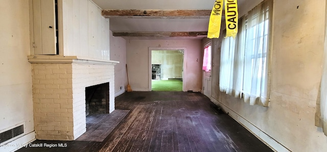 unfurnished living room featuring beamed ceiling, dark hardwood / wood-style floors, baseboard heating, and a brick fireplace