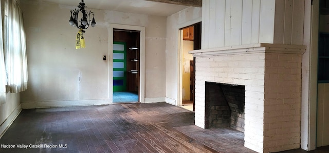 unfurnished living room featuring a fireplace, dark hardwood / wood-style floors, and an inviting chandelier