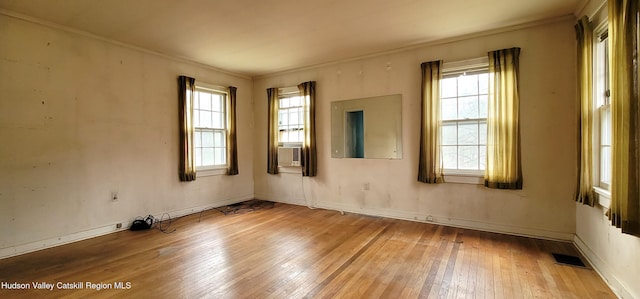 unfurnished room featuring crown molding, cooling unit, a healthy amount of sunlight, and wood-type flooring