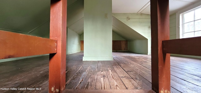 bonus room with dark hardwood / wood-style flooring, vaulted ceiling, and wood walls