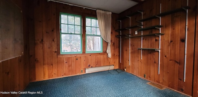 carpeted spare room featuring a baseboard radiator and wood walls