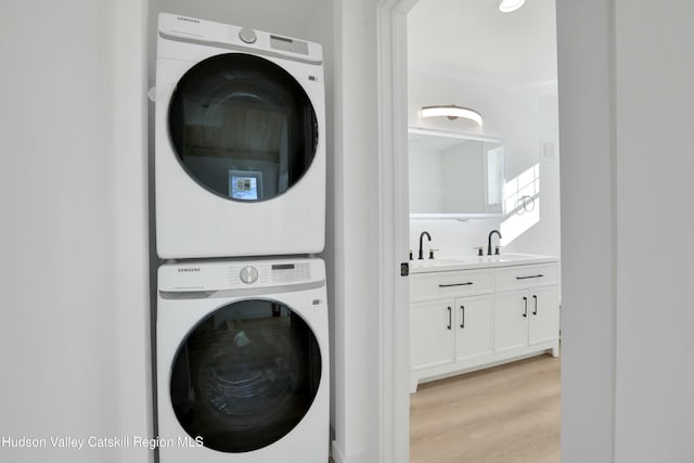 laundry room with light wood-type flooring, stacked washer / dryer, and sink