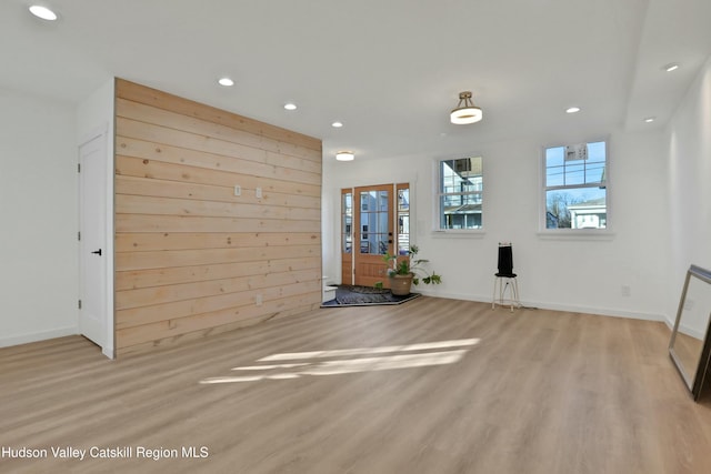 interior space with light wood-type flooring and wooden walls