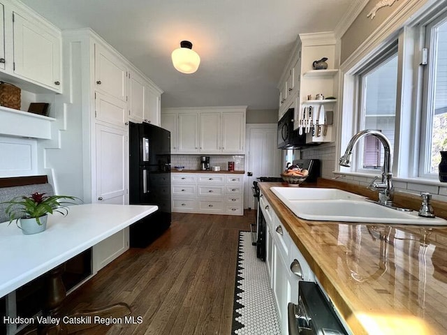 kitchen featuring a sink, butcher block counters, black appliances, tasteful backsplash, and white cabinetry