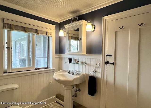 bathroom with wainscoting, plenty of natural light, visible vents, and a sink