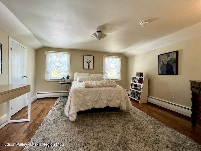 bedroom with lofted ceiling, wood finished floors, a baseboard heating unit, and multiple windows