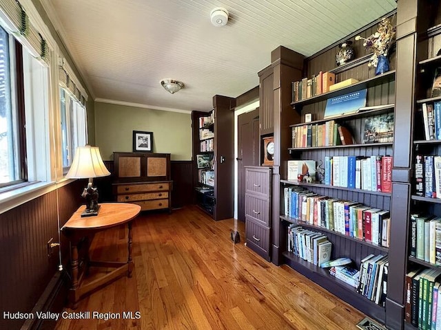 living area with wainscoting, ornamental molding, wood finished floors, and wooden walls