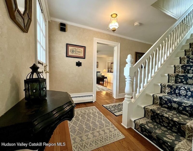 entrance foyer featuring a baseboard heating unit, stairway, ornamental molding, and wood finished floors