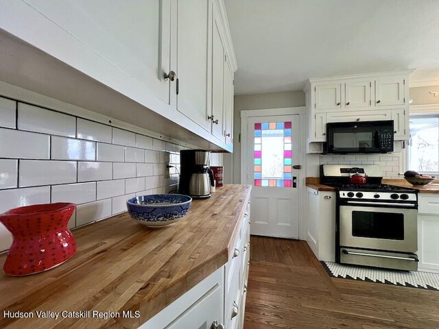 kitchen with black microwave, gas stove, decorative backsplash, and butcher block countertops