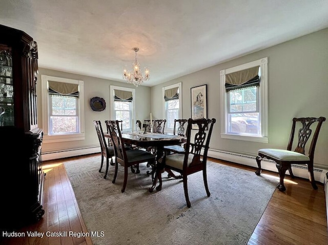 dining room with baseboard heating, an inviting chandelier, and hardwood / wood-style flooring