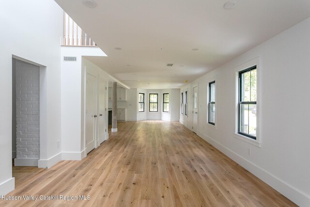 hallway with a wealth of natural light and light hardwood / wood-style flooring