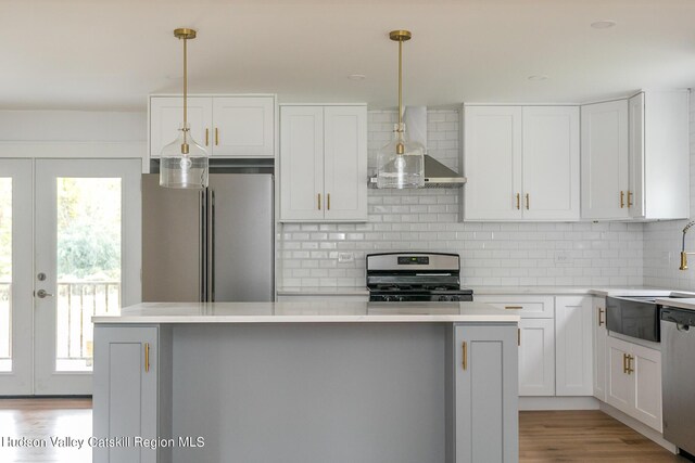 kitchen featuring decorative light fixtures, a center island, stainless steel appliances, and white cabinetry