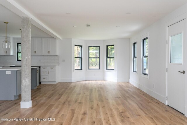 unfurnished living room with decorative columns and light hardwood / wood-style floors