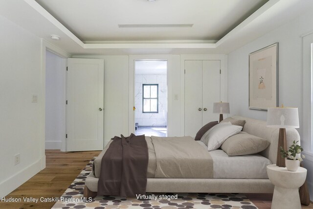 bedroom featuring hardwood / wood-style flooring and a raised ceiling