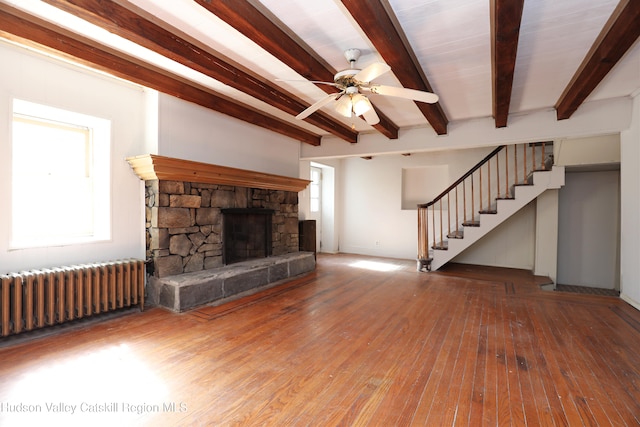 651 Glasco Tpke, Saugerties, NY 12477 - unfurnished living room with radiator, beam ceiling, a stone fireplace, ceiling fan, and hardwood / wood-style flooring