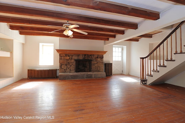 651 Glasco Tpke, Saugerties, NY 12477 - unfurnished living room featuring a stone fireplace, beamed ceiling, a ceiling fan, and radiator heating unit