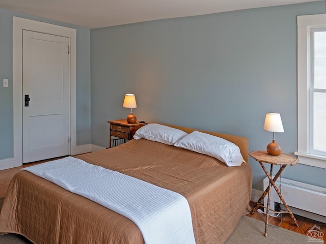bedroom featuring multiple windows, baseboards, and wood finished floors