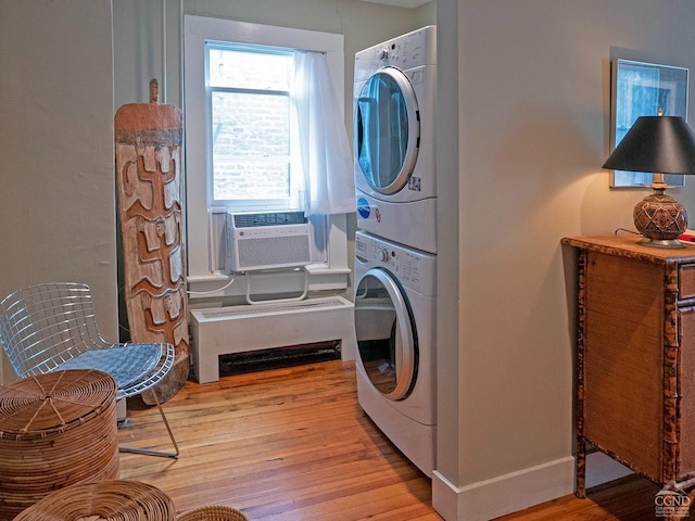 laundry area featuring estacked washer and dryer, cooling unit, light wood finished floors, and baseboards