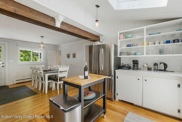 kitchen featuring stainless steel refrigerator, white cabinetry, tasteful backsplash, lofted ceiling with skylight, and pendant lighting