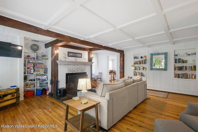 living room featuring hardwood / wood-style floors, built in features, coffered ceiling, and a brick fireplace