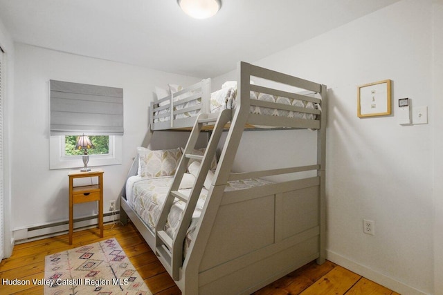 bedroom featuring hardwood / wood-style floors and a baseboard heating unit