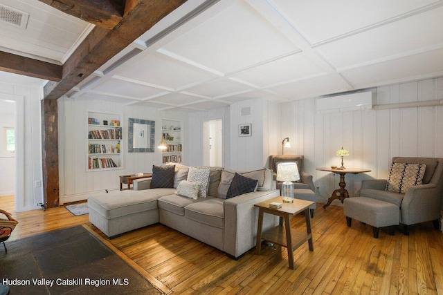 living room with a wall unit AC, built in features, wood-type flooring, and coffered ceiling