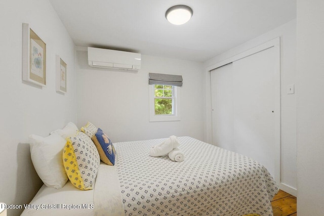 bedroom with hardwood / wood-style floors, a closet, and a wall mounted AC