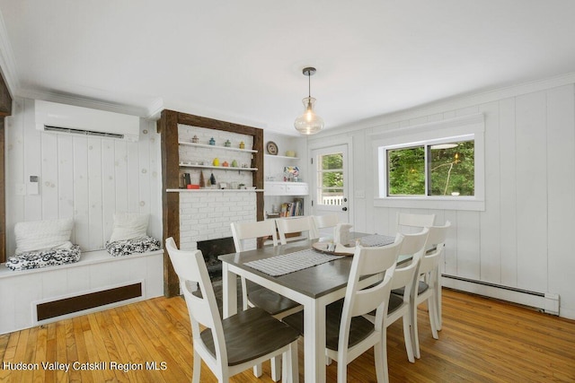 dining room with wooden walls, light hardwood / wood-style flooring, a baseboard radiator, and a wall mounted air conditioner