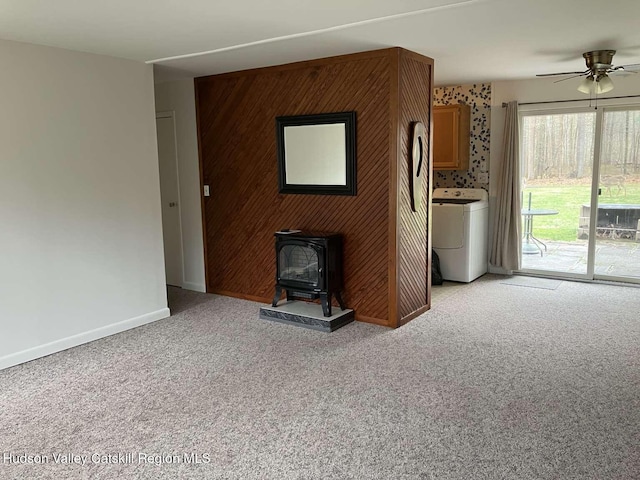 44 Overlook Dr, Woodstock, NY 12498 - unfurnished living room with washer / clothes dryer, a wood stove, light carpet, ceiling fan, and wood walls