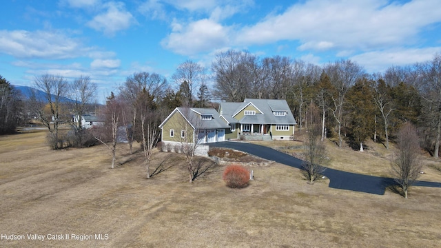 view of front of house featuring an attached garage, covered porch, aphalt driveway, and a front yard