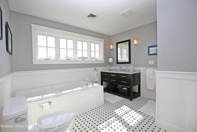 full bathroom with wainscoting, visible vents, toilet, and a bath