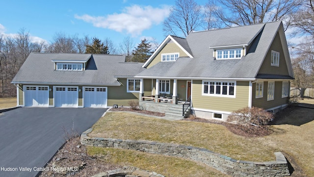 view of front of house with aphalt driveway, a front yard, covered porch, and a shingled roof