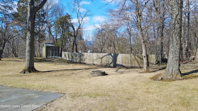 view of yard with an outdoor fire pit, fence, an outbuilding, and a shed