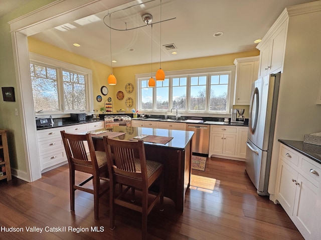 kitchen with visible vents, dark wood finished floors, white cabinets, stainless steel appliances, and a sink