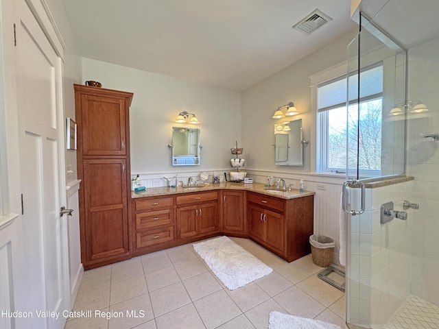 full bath featuring tile patterned flooring, visible vents, a sink, and a shower stall