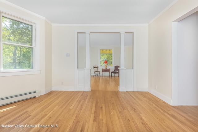 spare room featuring baseboards, ornamental molding, light wood finished floors, and a baseboard heating unit