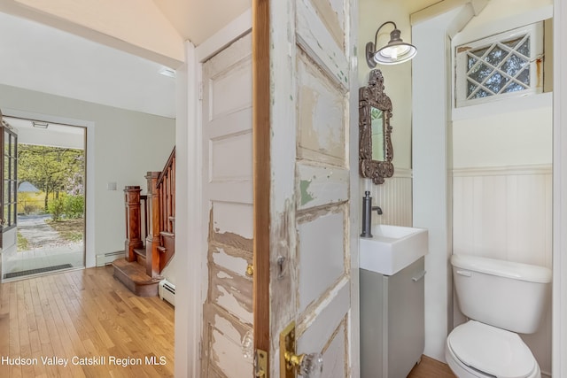 bathroom featuring wood finished floors, baseboard heating, and toilet